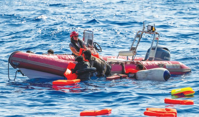 An NGO crew member helps migrants to get onboard after their wooden boat overturned during a rescue operation at the Mediterranean Sea. (AP)