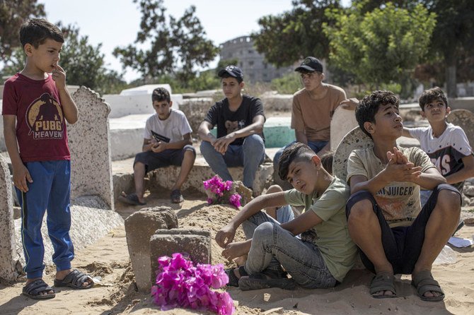 Relatives of the children of the Nijim family, who were killed in an Israeli raid, sit around their graves at Al-Faluja cemetery in Jabalia, in the northern Gaza Strip, on Aug.8, 2022. (AP)