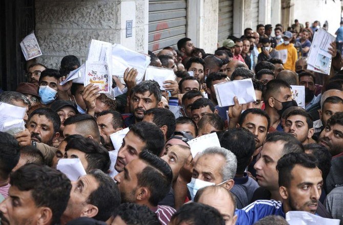 Above, Palestinian men gather to apply for work permits in Israel at Jabalia refugee camp in the northern Gaza Strip on Oct. 6, 2021. (AFP file photo)