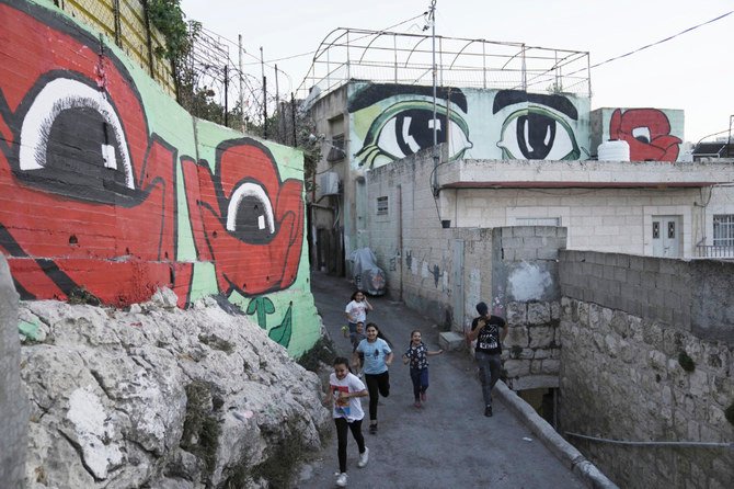 Palestinian children walk between murals that are part of the public art project ‘I Witness Silwan,’ in the Silwan neighborhood of East Jerusalem. (AP)