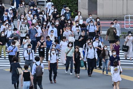 People cross the street in the Shinjuku district of Tokyo on August 16, 2022. (AFP)