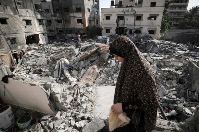 A Palestinian woman walks through rubble in front of her home in Gaza city early on August 8, 2022, following a cease fire between Israel and Palestinian militants. (AFP)