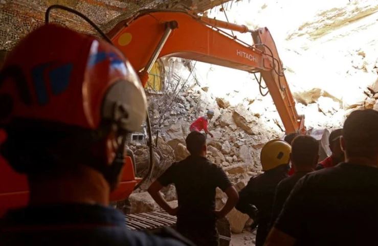Iraqi rescue workers search for survivors trapped under the rubble of the Qattarat Al-Imam Ali shrine in Karbala on Aug. 21, 2022. (AFP)