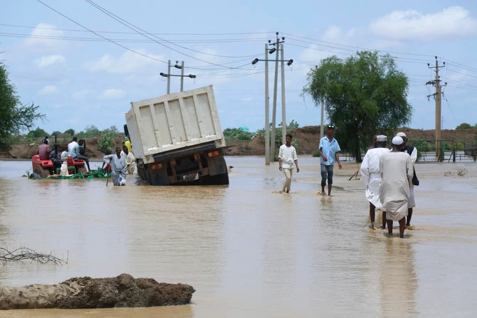 People walk on a flooded road near the village of Aboud in El Manaqil district, Sudan, Thursday, Aug. 18, 2022. (AP)