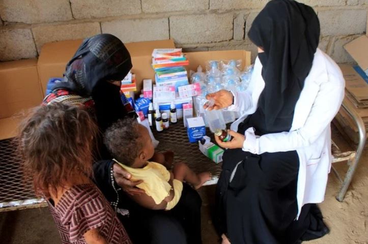 Volunteer health worker Ashwaq Mahmoud checks a medicine as she helps a child in Abs, Yemen September 13, 2021. (Reuters)