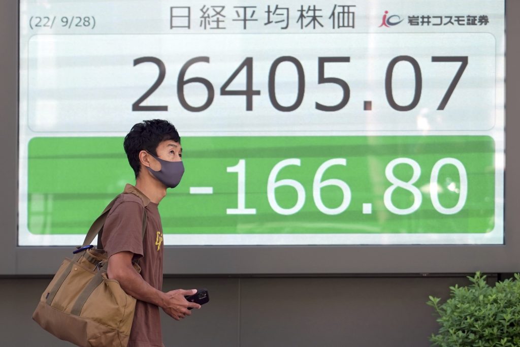 A person wearing a protective mask walks in front of an electronic stock board showing Japan's Nikkei 225 index at a securities firm, Sept. 28, 2022, in Tokyo. (File photo/AP)