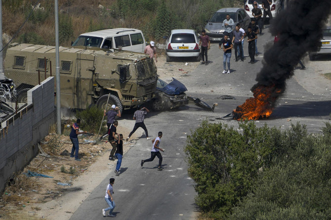 Palestinians hurl rocks at Israeli military vehicles during an army operation in the West Bank village of Rujib earlier this week. (AP)