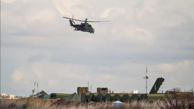 A Russian Mi-24 helicopter gunship flies on patrol while S-400 air defense missile systems are seen in the background, bottom, at Hemeimeem air base in Syria on Wednesday Jan. 20, 2016 (AP)