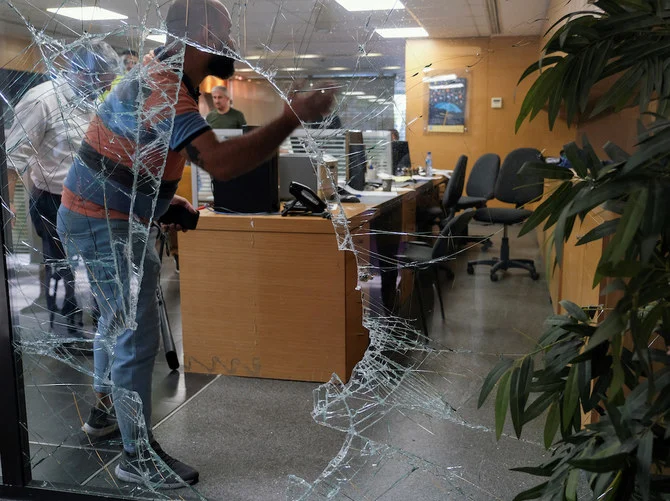 Men are seen through a shattered window of a Blom Bank branch in Beirut. (Reuters)