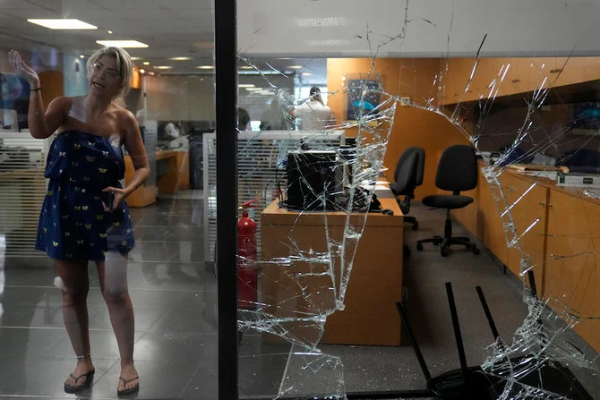 A woman is seen through a shattered window of a Blom Bank branch in Beirut. (Reuters)