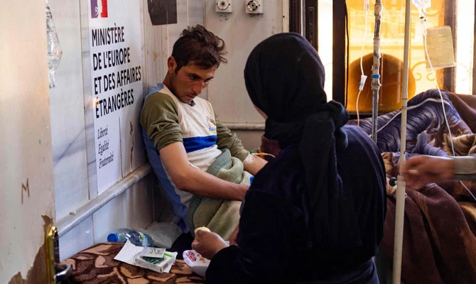 A young man suffering from cholera receives treatment at the Al-Kasrah hospital in Syria's eastern province of Deir Ezzor, on 17, 2022, affected by the usage of contaminated water from the Euphrates River, a major source for both drinking and irrigation. (AFP)