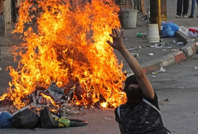 A Palestinian protester sits next to burning tires amid clashes with Israeli security forces in the city of Hebron, in the occupied West Bank, Sept. 28, 2022. (AFP)