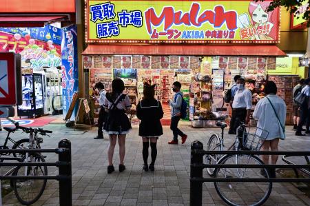 Pedestrians walk past a shop in the popular electronics shopping area of Akihabara in Tokyo on September 21, 2022. (AFP)