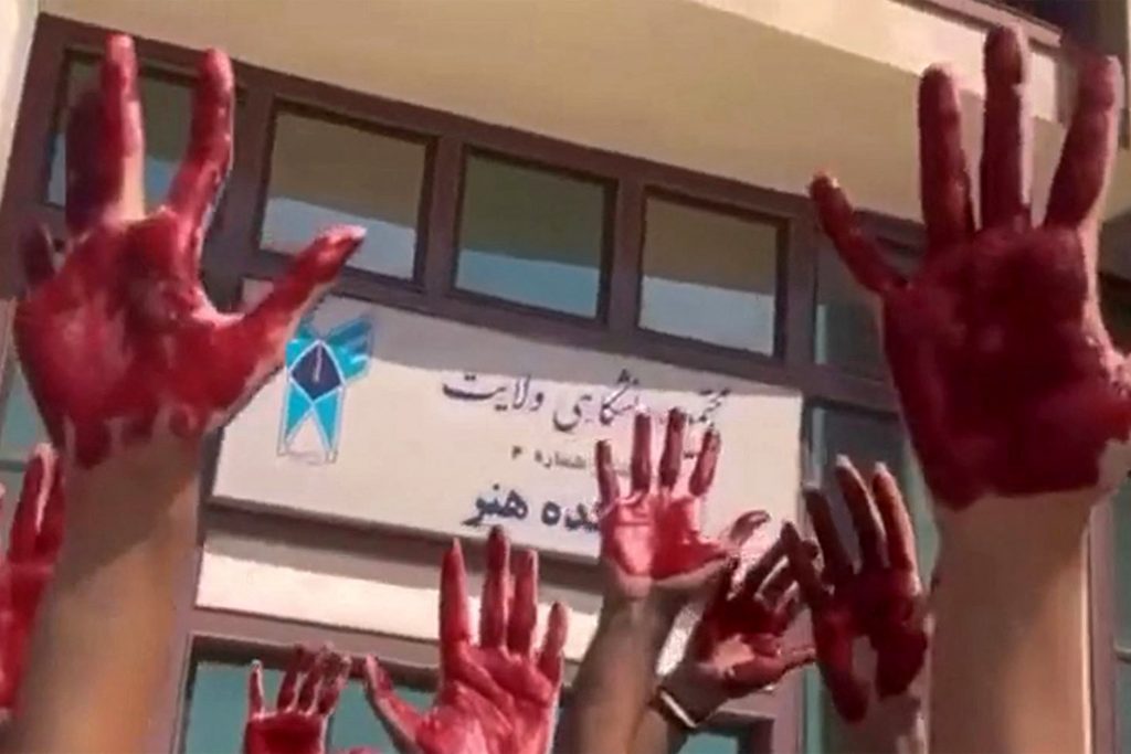 Students of Tehran’s Azad University protest with their palms covered in red paint to symbolize the blood of slain demonstrators. (AFP)
