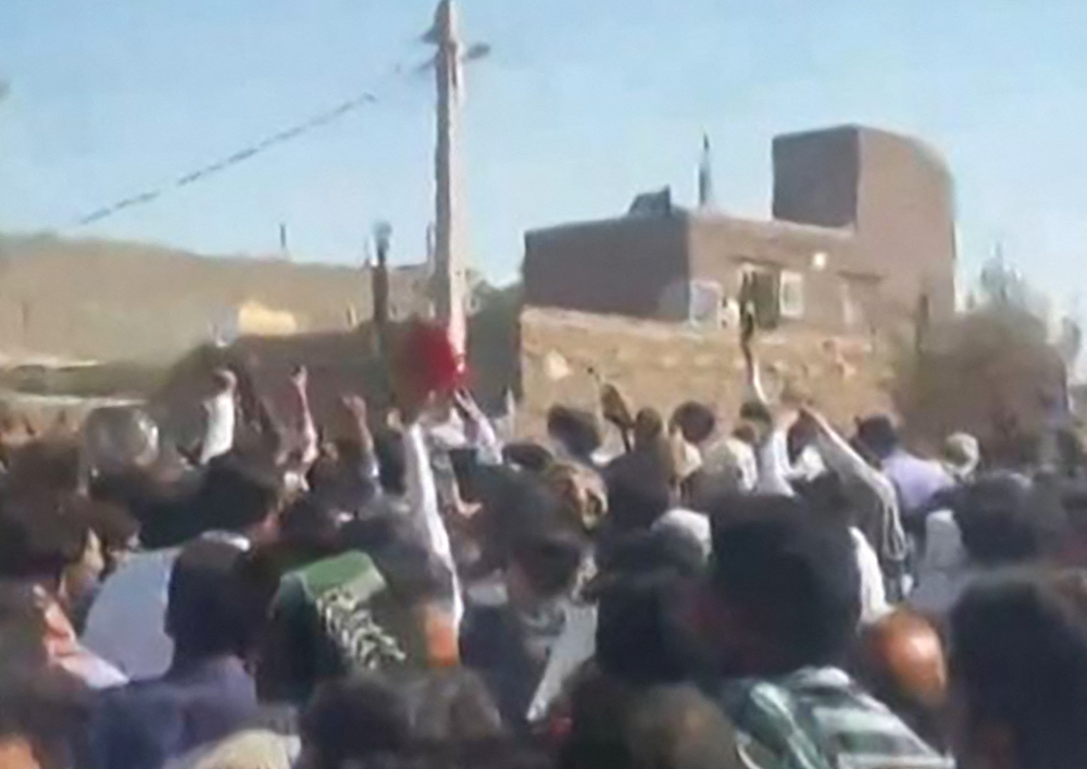 This grab from a UGC video posted on October 21, 2022, shows demonstrators gesturing as they march on a street in the southeastern Iranian city of Zahedan. (AFP)