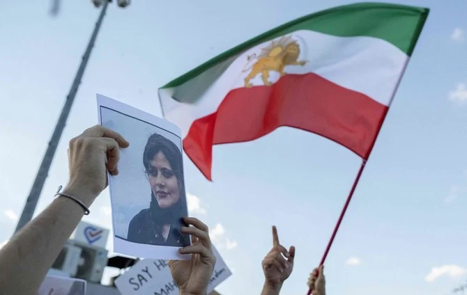 A protestor holds a photo of Mahsa Amini as another waves Iran's former flag during a demonstration against the Iranian regime in Istanbul. (AFP)