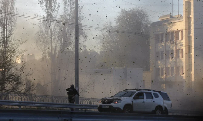 A police officer watches stone and earth debris flying through the air as Russian kamikaze drones hit the center of the capital Kyiv, Ukraine on Monday, Oct. 17, 2022. (AP)