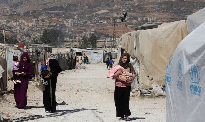 Syrian refugee women carry children as they walk at an informal camp, in the Bekaa Valley, Lebanon October 18, 2022. (Reuters)