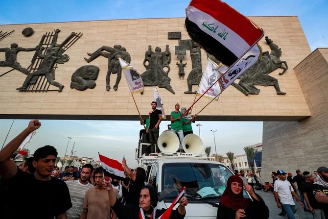 Demonstrators wave Iraqi national flags before the Liberty Monument in the capital’s Tahrir Square on October 25, 2022, during a protest against the new government of new Prime Minister Mohammed Shia Al-Sudani. (AFP)