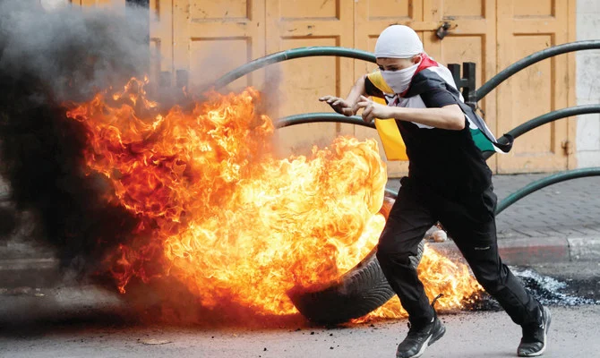 A Palestinian runs next to a burning tire during clashes with Israeli forces in Hebron in the Israeli-occupied West Bank. (Reuters/File)