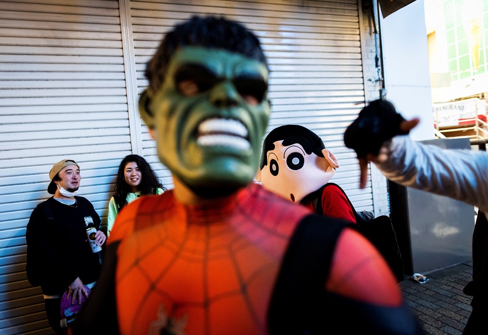 People wearing a Hulk (centre) and a Shin-chan (right) costume pose during a Halloween parade at Shibuya district in Tokyo on October 30, 2021. (AFP)
