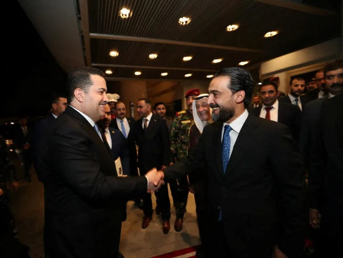 Iraqi Prime Minister-designate Mohammed Shia Al-Sudani shakes hands with Iraqi speaker of Parliament Mohammed Al-Halbousi, before a vote on Sudani’s cabinet at the parliament in Baghdad on Thursday. (Reuters)