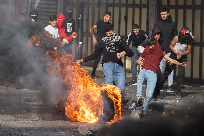 Palestinians react next to a burning tire during clashes with Israeli forces in Hebron in the Israeli-occupied West Bank on Sunday. (Reuters/File)