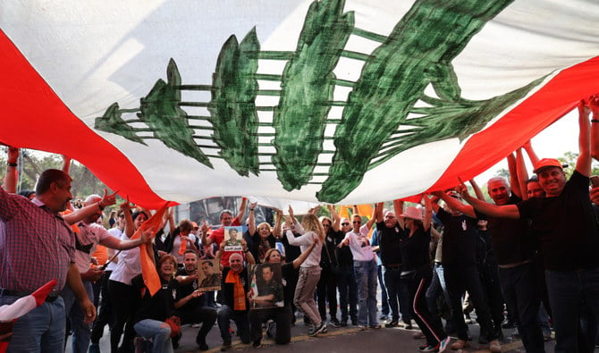 Supporters of Lebanon's President Michel Aoun cheer under a large national flag, as he prepares to leave the presidential palace in Baabda at the end of his mandate, east of the capital Beirut, on October 30, 2022. (AFP/File)