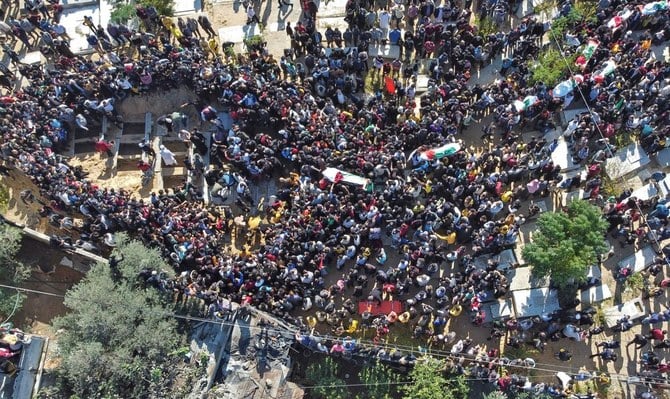 This aerial view shows Palestinians carrying the flag-draped bodies of people who died a day earlier, when fire broke out in an apartment, in the Jabalia refugee camp in the northern Gaza strip, on Friday. (AFP)