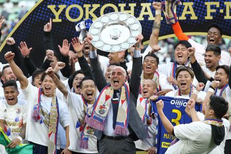 Yokohama F Marinos manager Kevin Muscat (centre) holds up the trophy as he celebrates with teammates after taking Japan's professional J-League football title following their 3-1 victory over Vissel Kobe to put them at the top of the standings, in Kobe on November 5, 2022. (AFP)