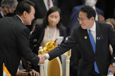 Japan's Prime Minister Fumio Kishida (right) shakes hands with South Korea's President Yoon Suk-yeol during the ASEAN Summit in Phnom Penh, Cambodia, Sunday. (AP)