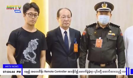In this image taken from video by Myanmar state broadcaster MRTV, Japanese national Toru Kubota (left) poses with unidentified officials at the Yangon International Airport in Yangon, Myanmar on Thursday, Nov. 17, 2022. (AP)