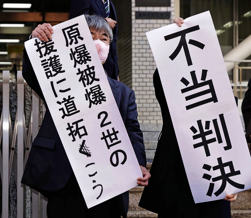 Noboru Sakiyama, left, head of the plaintiffs holds a banner at the Nagasaki District Court in Nagasaki, southern Japan Monday, Dec. 12, 2022. (File/Kyodo News via AP)