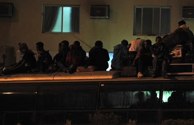 Above, illegal migrants on the top roof of a police bus in Riyadh ahead of their deportation in 2013. (AFP file photo)