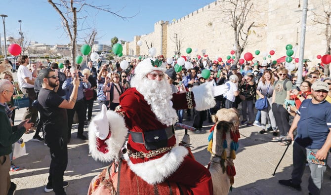 Palestinian Issa Kassissieh, dressed as Santa Claus, rides a camel at Jaffa Gate in Jerusalem’s Old City on Sunday, a few weeks before the upcoming holiday of Christmas. (AFP)