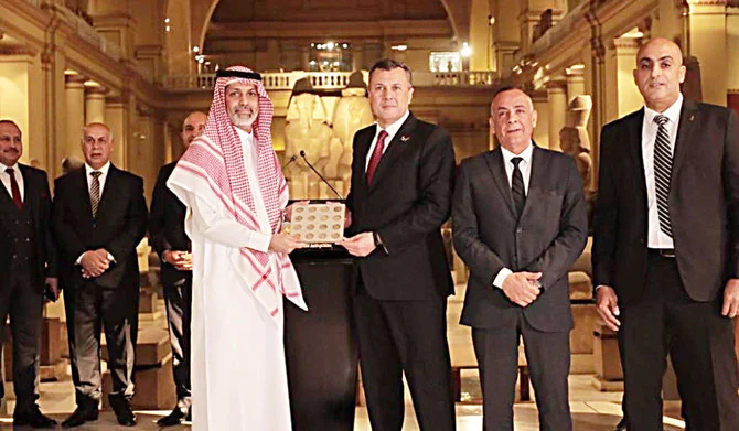 An Egyptian antiquity official hands over coins to a representative from Saudi Arabia in Cairo. (Supplied)