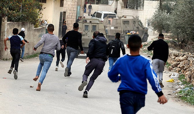 Palestinians pelt stones at Israeli military vehicles during an army raid in the village of Salem, east of Nablus, in the occupied West Bank, on Wednesday. (AFP)