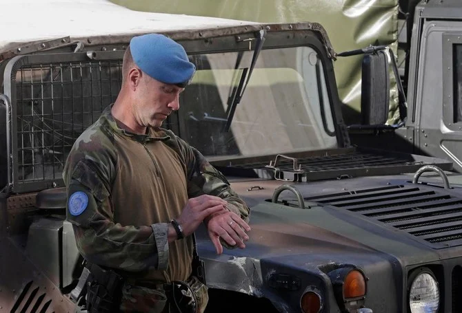 An Irish soldier checks the time as he waits outside Hammoud Hospital in the southern city of Sidon (Saida) on December 18, 2022 to transport the body of Irish soldier Sean Rooney to Beirut airport for repatriation. (AFP)