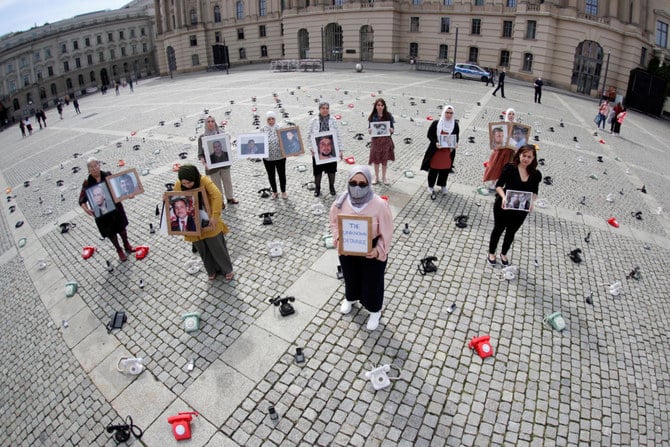People hold portraits and a placard during a protest as around 300 landline telephones placed by Syrian families stand at the Bebelplatz as a call to governments to do more to seek information about detained people in Syria. (Reuters)