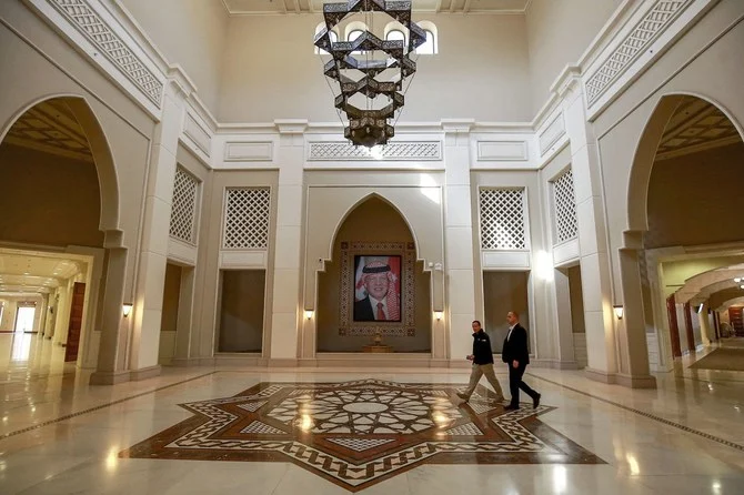 Men walk near a framed picture depicting Jordan's reigning King Abdullah II as they cross the main hall at the King Hussein Bin Talal Convention Centre. (AFP)