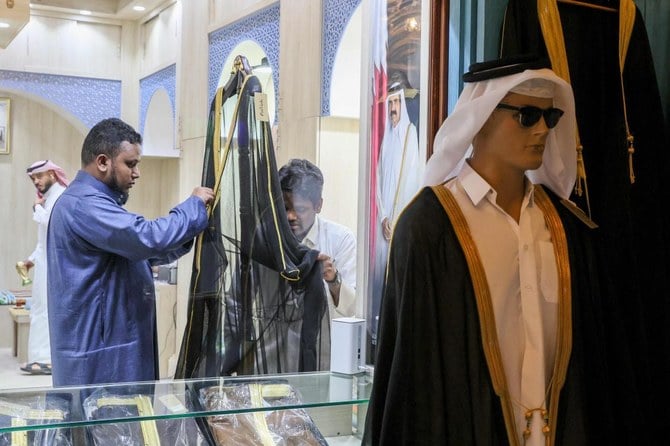 Qataris work on a bisht at the Al-Salim store in Doha's Souq Waqif market, on 20 December, 2022. (AFP)