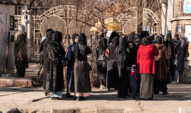 Afghan female university students stop by Taliban security personnel stand next to a university in Kabul on December 21, 2022. (AFP)