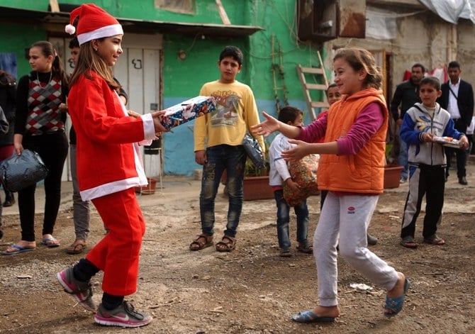 A Lebanese Christian girl dressed as Santa Claus, hands a gift to a Syrian refugee in the town of Dbayeh, north of Beirut. (AFP/File)