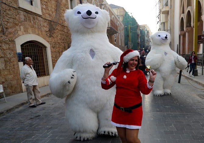 A Lebanese woman wearing a Santa Claus outfit parades with youths dressed as polar bears ahead of Christmas on December 11, 2020, along Gouraud street in the capital Beirut's Gemmayzeh neighbourhood. (AFP)