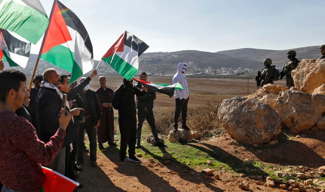 Israeli security forces take position as Palestinians wave national flags during a protest east of Nablus against the establishment of Israeli outposts, on December 2, 2022. (AFP/File)