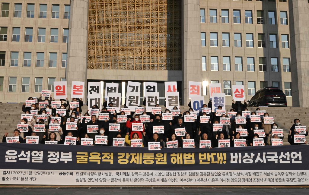 South Korean opposition lawmakers and supporters of the victims of Japan's wartime forced labour hold placards reading 