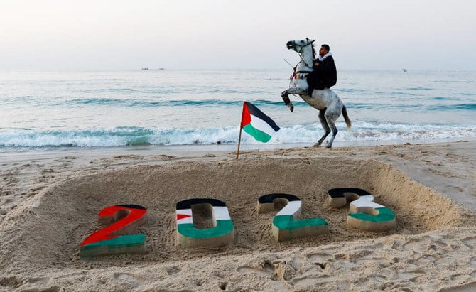 A man rides his horse next to the 2023 sand sculpture on the beach in Gaza City during the last sunset of Dec. 31, 2022, as Palestinians bid farewell to a painful year in terms of human loss. (Reuters)