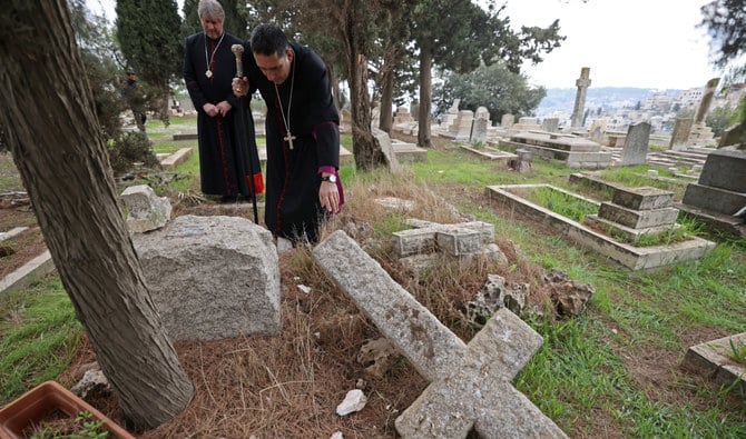 Hosam Naoum, archbishop and caretaker of the Protestant cemetery, inspects vandalised graves on Mount Zion outside Jerusalem's Old City on January 4, 2023. (AFP)