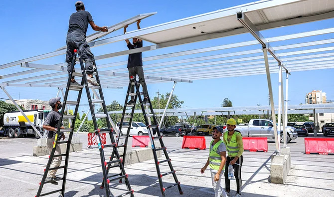 Workers install new solar panels as shades above vehicles in the parking garage of a shopping mall in the city of Byblos in northern Lebanon. (AFP/File)