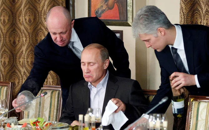 Evgeny Prigozhin (L) assists Russian Prime Minister Vladimir Putin during a dinner with foreign scholars and journalists at the restaurant Cheval Blanc on the premises of an equestrian complex outside Moscow November 11, 2011. (REUTERS)